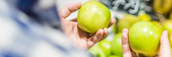 man comparing two green apples